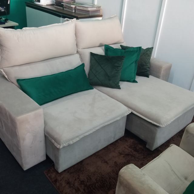 Sofá retrátil claro com almofadas verdes